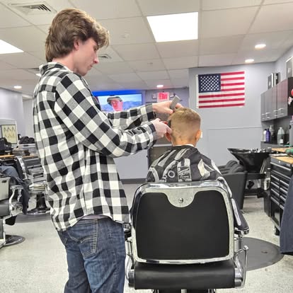 Barber cutting a young client's hair inside Tomasso's, Turnersville